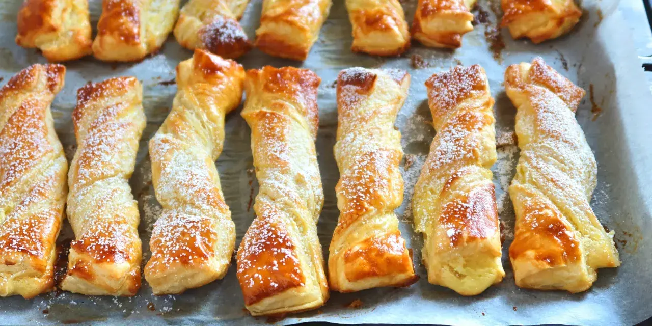Deliciosos lazos de hojaldre dorados y espolvoreados con azúcar glas, listos para disfrutar.