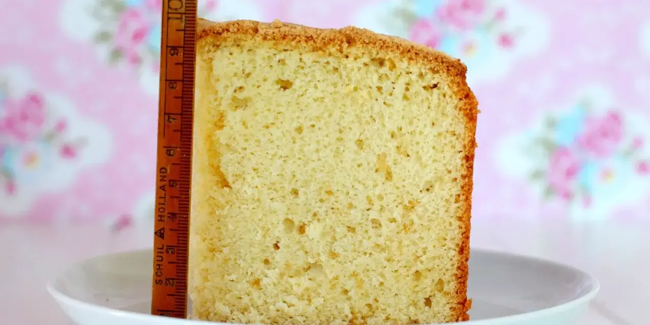 Rebanada de bizcocho de yogurt esponjoso, con una regla de madera al lado para medir su altura.