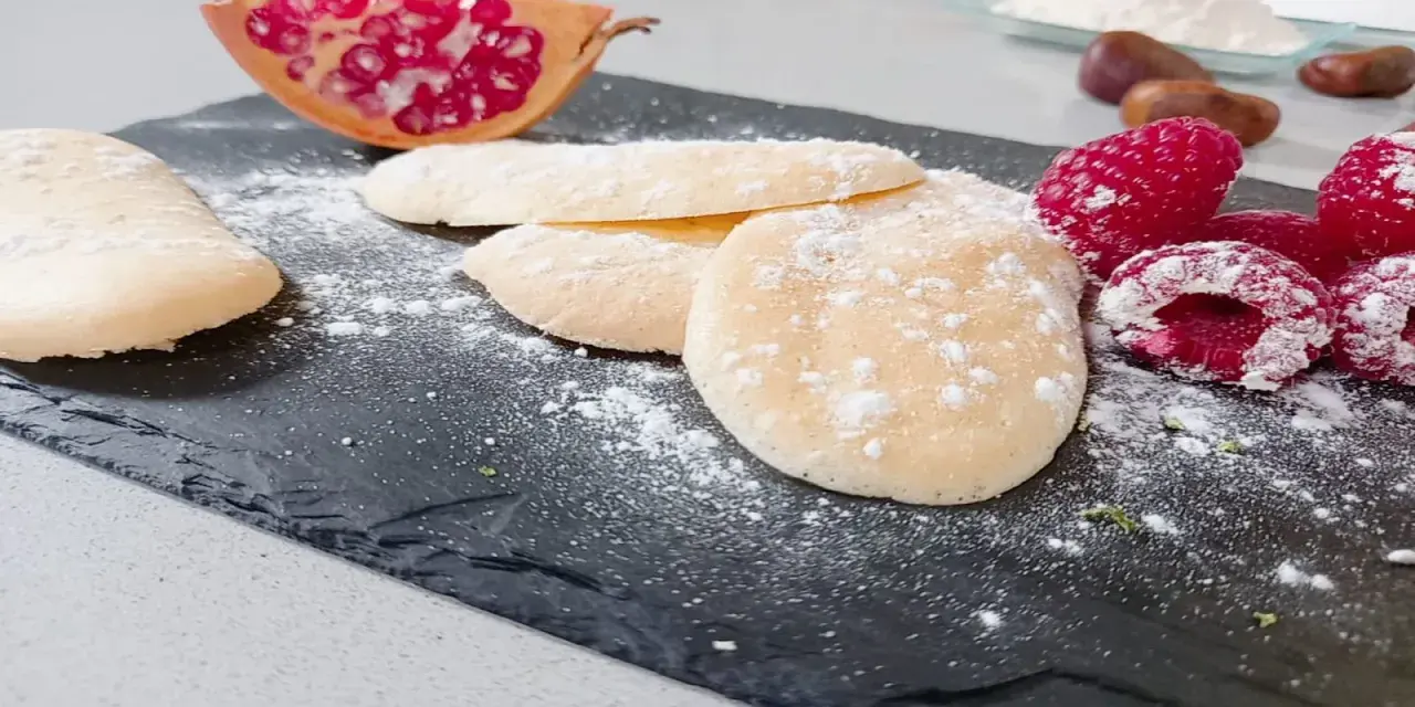 Bizcochos soletilla espolvoreados con azúcar glas, acompañados de frambuesas y granada.