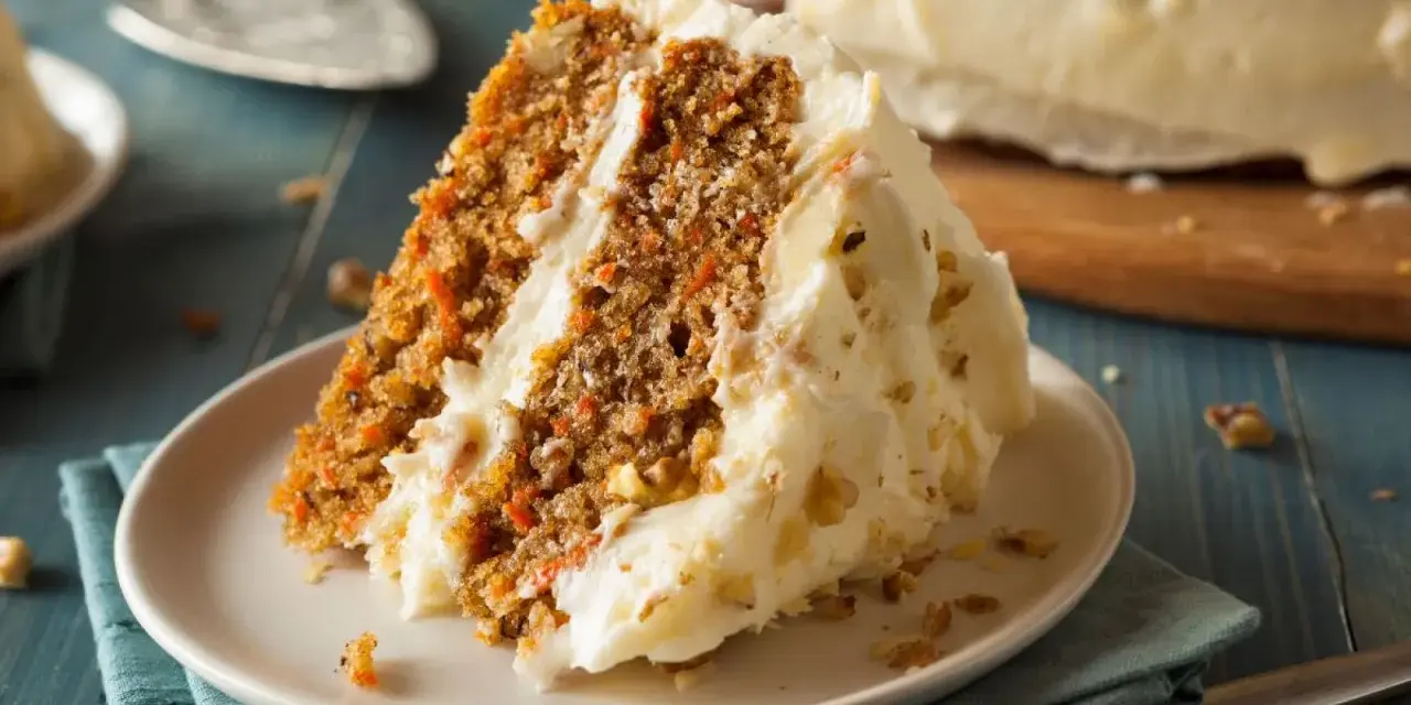 Rebanada de tarta de zanahoria casera con glaseado cremoso y nueces. ¡Una delicia para tu próxima receta!