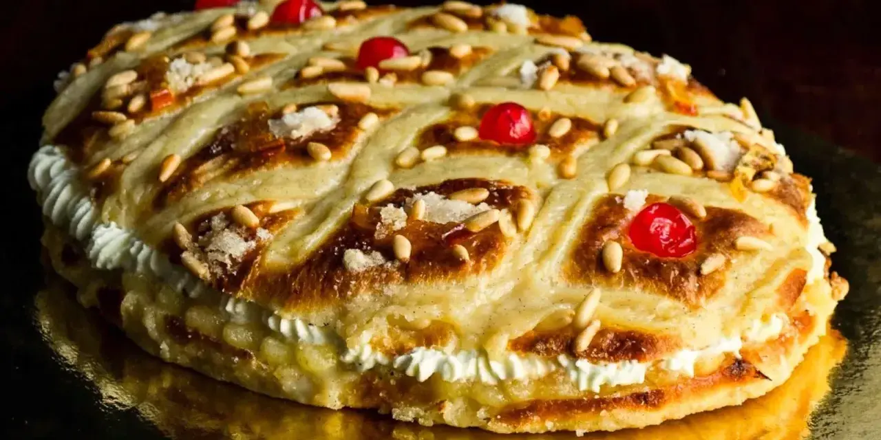 Deliciosa coca de Sant Joan rellena de crema, decorada con piñones, cerezas rojas y azúcar.