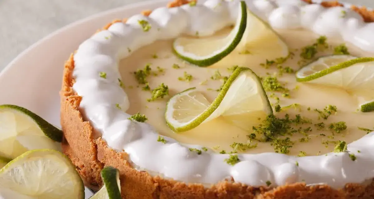 Delicioso key lime pie con merengue, rodajas de lima y ralladura verde.