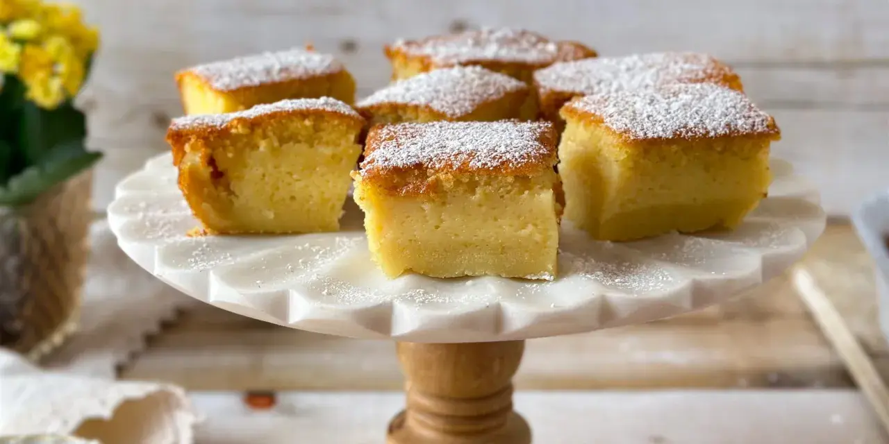 Porciones de un pastel mágico, cubiertas con azúcar glas, sobre un soporte de mármol.