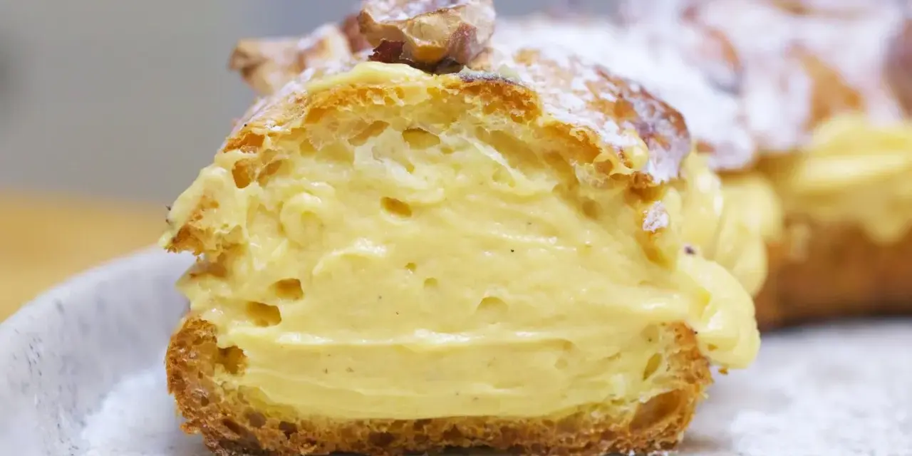 Un delicioso paris brest, un postre francés con crema pastelera y almendras, espolvoreado con azúcar glas.
