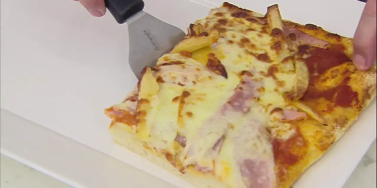 Una rebanada de pan pizza con papas fritas y jamón, lista para ser servida.