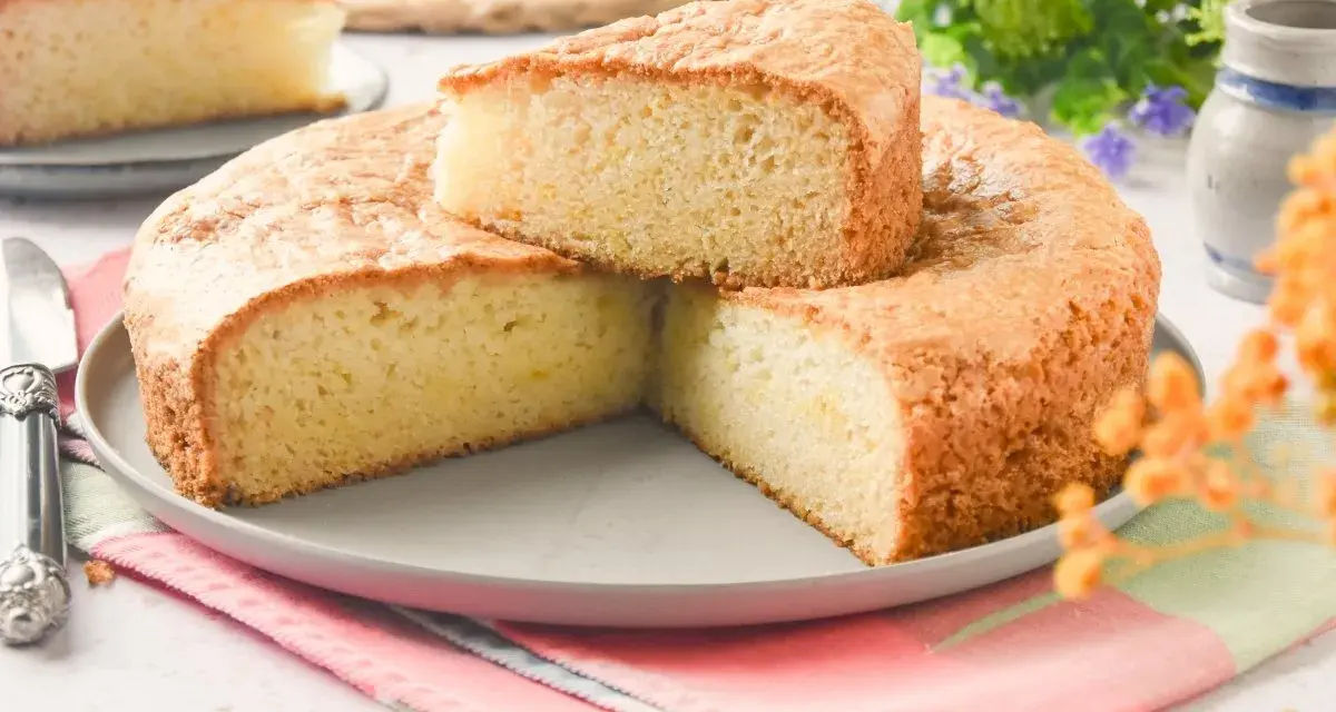 Bizcocho sin huevo esponjoso y dorado, cortado en porciones sobre un plato gris. Ideal para desayunos o meriendas.
