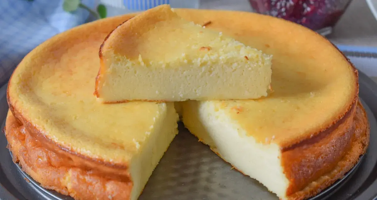 Tarta de queso y limón al horno, dorada y esponjosa, con una porción servida.