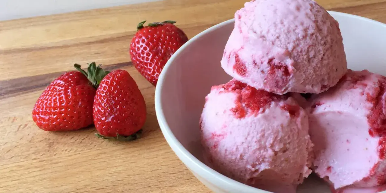 Delicioso helado de frutos rojos con fresas frescas al lado, listo para disfrutar en un día caluroso.