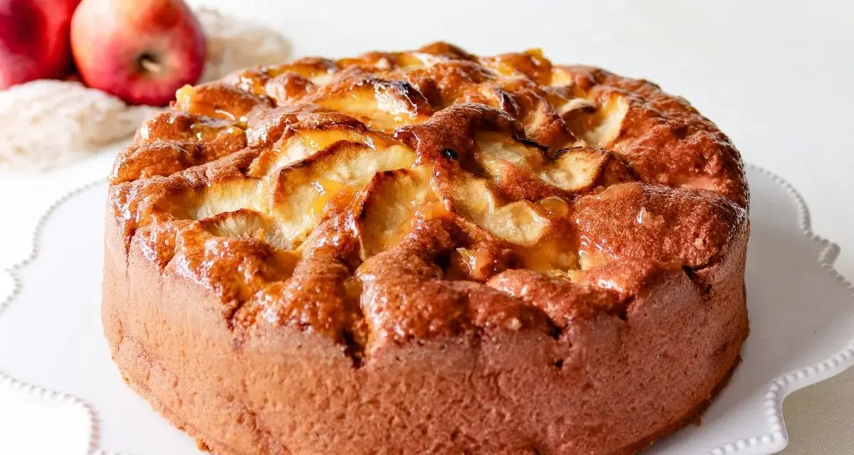 Bizcocho de manzana esponjoso, dorado y brillante, con trozos de manzana caramelizada en la superficie. ¡Perfecto para tu próxima receta!