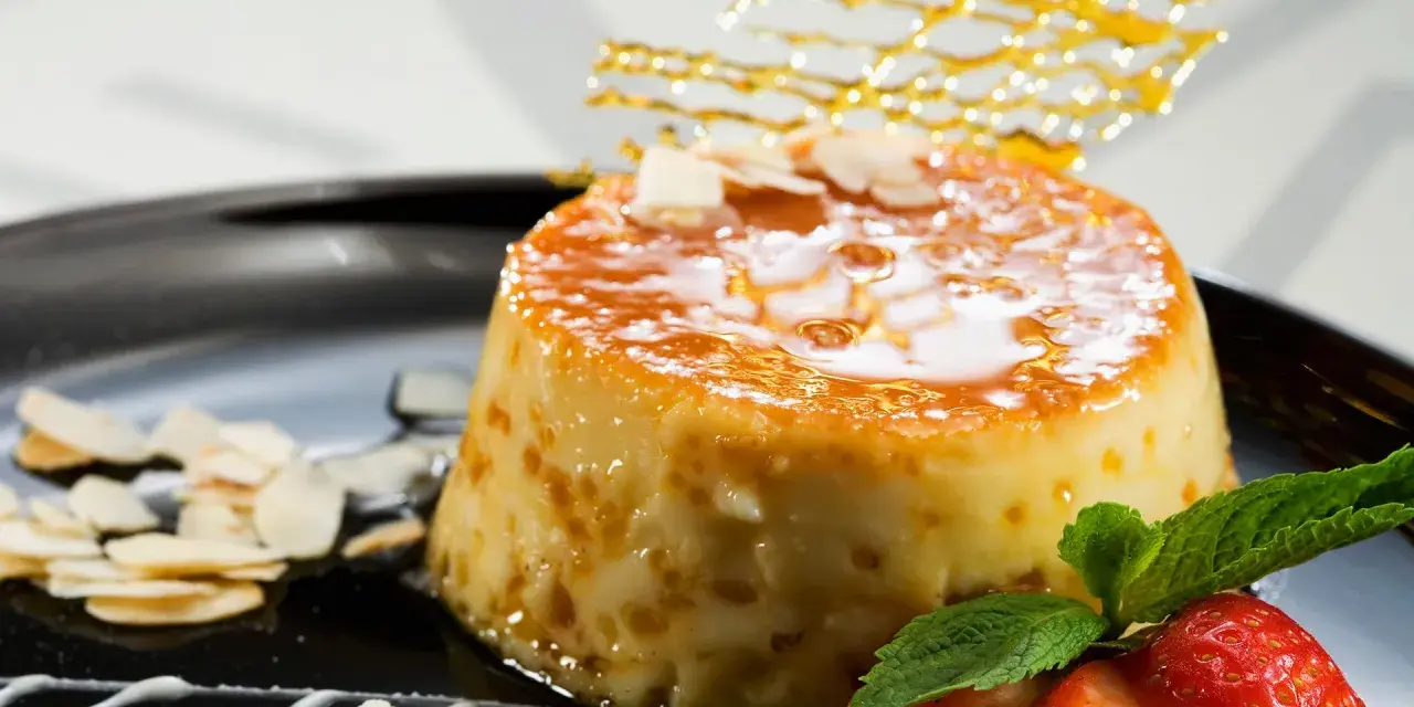 Delicioso postre de piña y leche condensada, cubierto de caramelo y decorado con almendras y fresas.