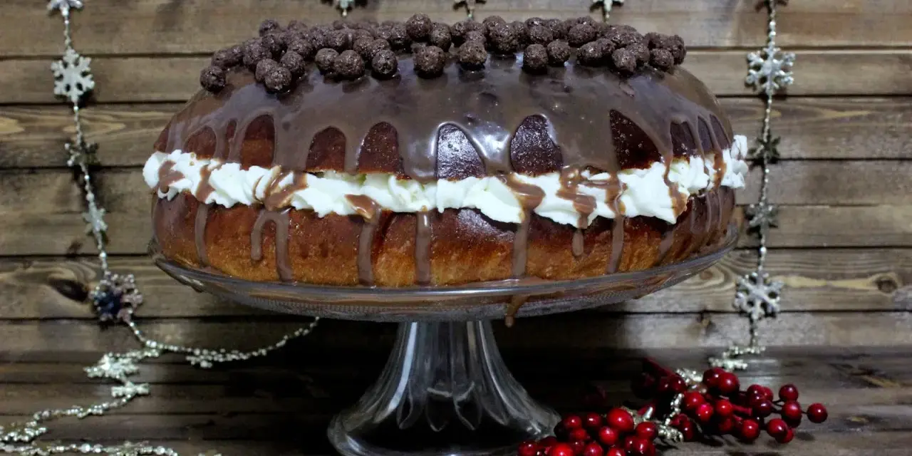 Un delicioso roscon de reyes chocolate, cubierto de glaseado y bolitas de chocolate, con crema y decoraciones navideñas.