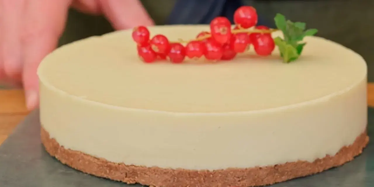 Deliciosa tarta de chocolate blanco, decorada con grosellas rojas y una hoja de menta.