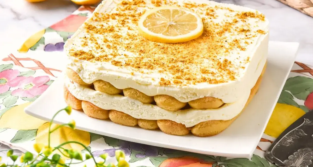 Delicioso tiramisú de limón, con capas de bizcochos y crema, coronado con una rodaja de limón y ralladura dorada.