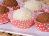 Deliciosas trufas de coco y chocolate, algunas cubiertas de coco rallado y otras de cacao en polvo, presentadas en capacillos rojos con puntos blancos.