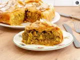 Pastela marroqui, un pastel salado de hojaldre relleno de pollo y especias, servido en un plato decorado.