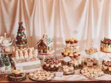 Mesa llena de postres navideños: árbol de macarons, casa de jengibre, muñecos de nieve, cupcakes y galletas.
