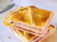 Dos porciones de empanadillas de jamón y queso, con capas doradas de masa y relleno generoso, listas para disfrutar.