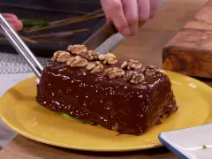 Un delicioso bizcocho de plátano cubierto de chocolate brillante y nueces, listo para ser cortado.