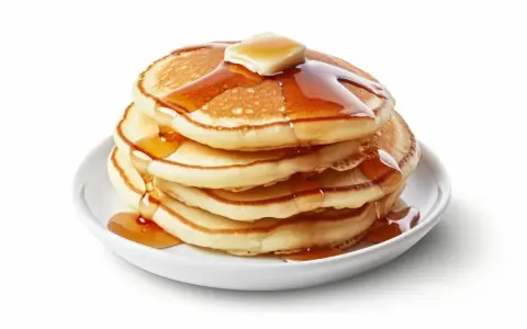 Pila de pancakes dorados con mantequilla y sirope cayendo. ¡Perfectos para tu receta de pancakes!