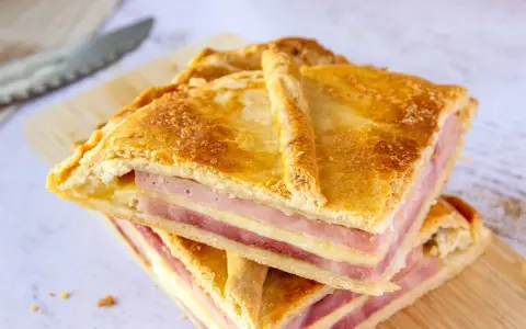 Dos porciones de empanadillas de jamón y queso, con capas doradas de masa y relleno generoso, listas para disfrutar.