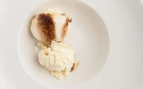 Dos bolas de helado de tiramisú con un toque de cacao en polvo en un cuenco blanco.