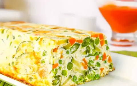 Pastel de verduras casero, con guisantes, zanahoria y calabacín, servido en un plato blanco.