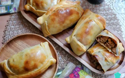 Deliciosas empanadas chilenas doradas, una rellena de carne cortada para mostrar su jugoso interior.