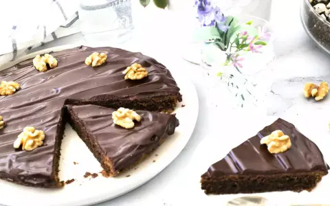 Delicioso pastel alemán de chocolate cubierto con glaseado brillante y nueces. Una rebanada ya servida.
