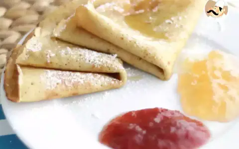 Deliciosos crepes sin gluten, espolvoreados con azúcar glas y acompañados de mermelada de fresa y melocotón.