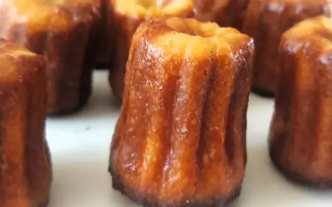 Un grupo de canelés de Bordeaux, con su característica corteza dorada y acanalada, listos para ser disfrutados.