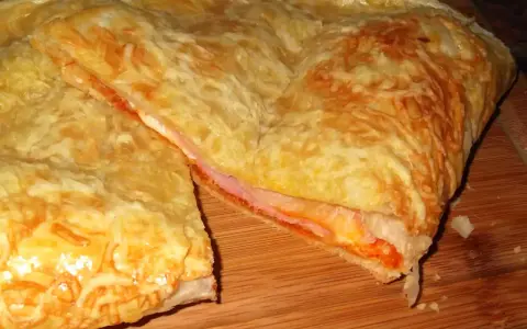 Empanada de jamón y queso dorada, con queso gratinado y relleno jugoso. ¡Un bocado delicioso!