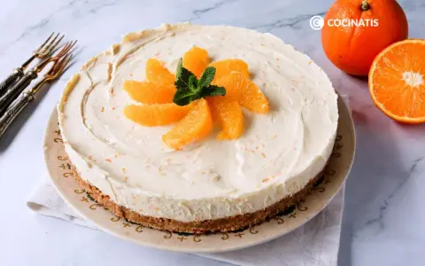 Tarta de naranja cremosa, decorada con gajos de naranja y menta. Perfecta para disfrutar de un postre refrescante.