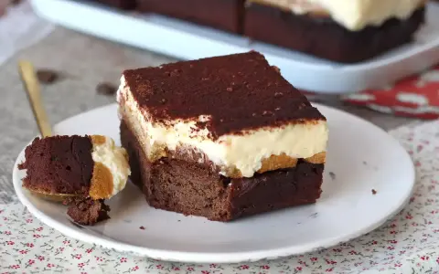 Un trozo de brownie de chocolate con una capa cremosa y espolvoreado de cacao. ¡Un delicioso brownie chocolate blanco!