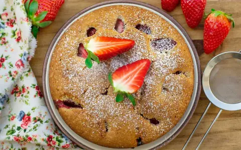 Delicioso bizcocho de fresa, espolvoreado con azúcar glas y decorado con fresas frescas. Un postre casero perfecto.