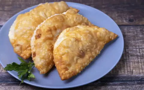 Tres empanadas doradas y crujientes, perfectas para tus recetas con obleas de empanadillas. Decoradas con perejil fresco.