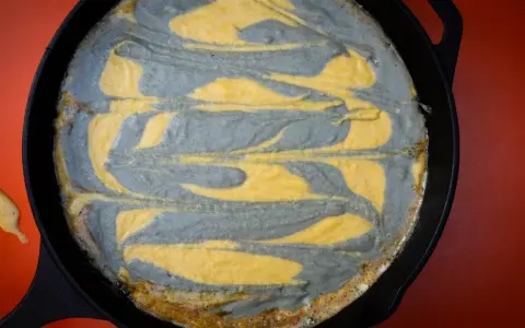 Pastel de maíz con remolinos grises y amarillos en una sartén de hierro fundido.