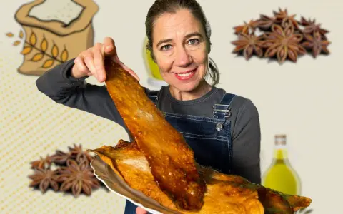 Mujer sonriente muestra una coca de vidre dorada, con ingredientes como harina, anís y aceite de oliva de fondo.