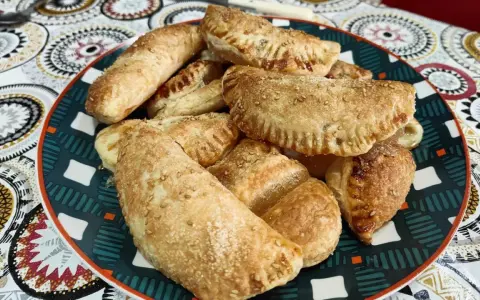 Plato lleno de empanadillas de cabello de ángel, doradas y espolvoreadas con semillas de sésamo.