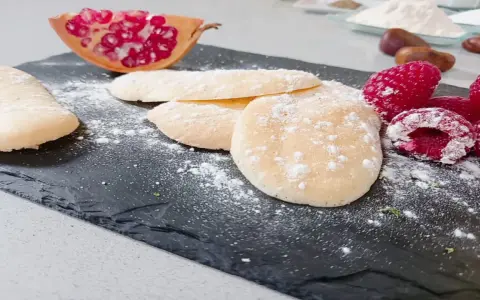 Bizcochos soletilla espolvoreados con azúcar glas, acompañados de frambuesas y granada.