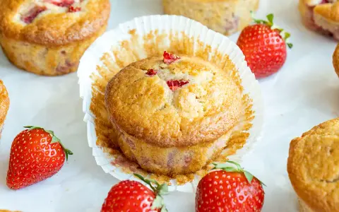 Delicioso postre con fresas, muffins dorados con trozos de fresa y fresas frescas alrededor.