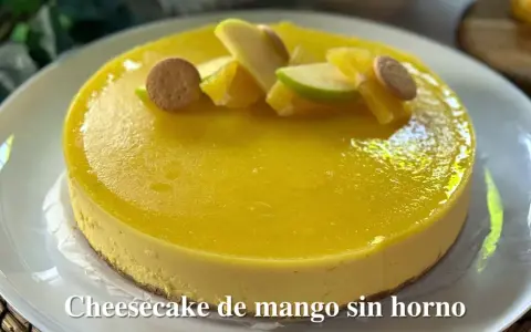 Tarta de queso y mango sin horno, decorada con trozos de manzana, naranja y galletas. ¡Un postre refrescante y delicioso!