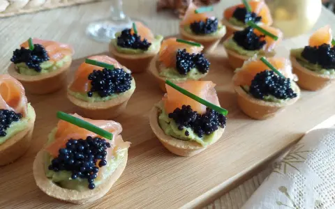 Deliciosas tartaletas de salmón y aguacate, coronadas con caviar negro y cebollino. Un bocado elegante y sabroso.