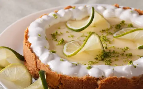 Delicioso key lime pie con merengue, rodajas de lima y ralladura verde.