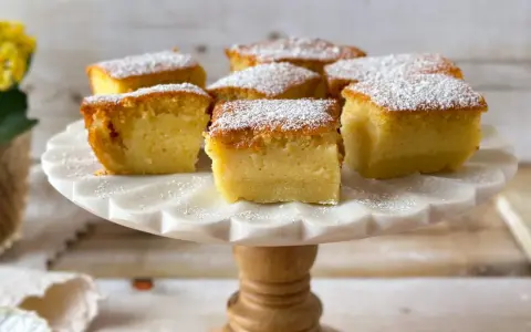 Porciones de un pastel mágico, cubiertas con azúcar glas, sobre un soporte de mármol.
