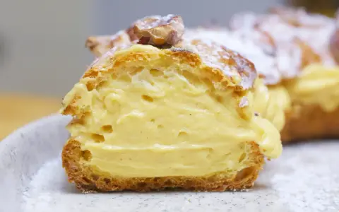 Un delicioso paris brest, un postre francés con crema pastelera y almendras, espolvoreado con azúcar glas.