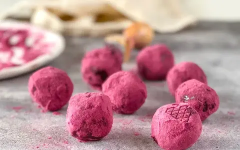 Deliciosas trufas de chocolate cubiertas de polvo rosa vibrante, algunas con un patrón grabado.