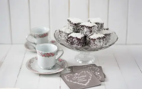Deliciosos lamington cake cubiertos de coco, listos para disfrutar con café.