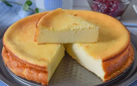 Tarta de queso y limón al horno, dorada y esponjosa, con una porción servida.