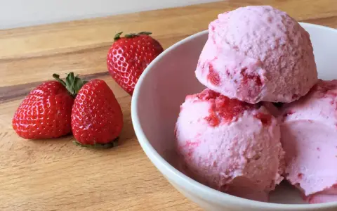 Delicioso helado de frutos rojos con fresas frescas al lado, listo para disfrutar en un día caluroso.