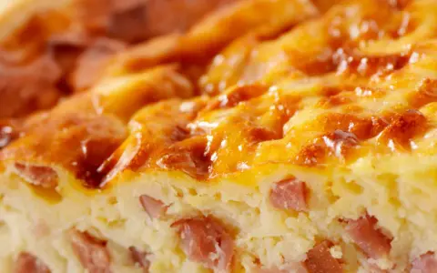 Primer plano de una deliciosa quiche Lorraine, con trozos de bacon y una dorada capa superior. ¡Perfecta para tu próxima receta!